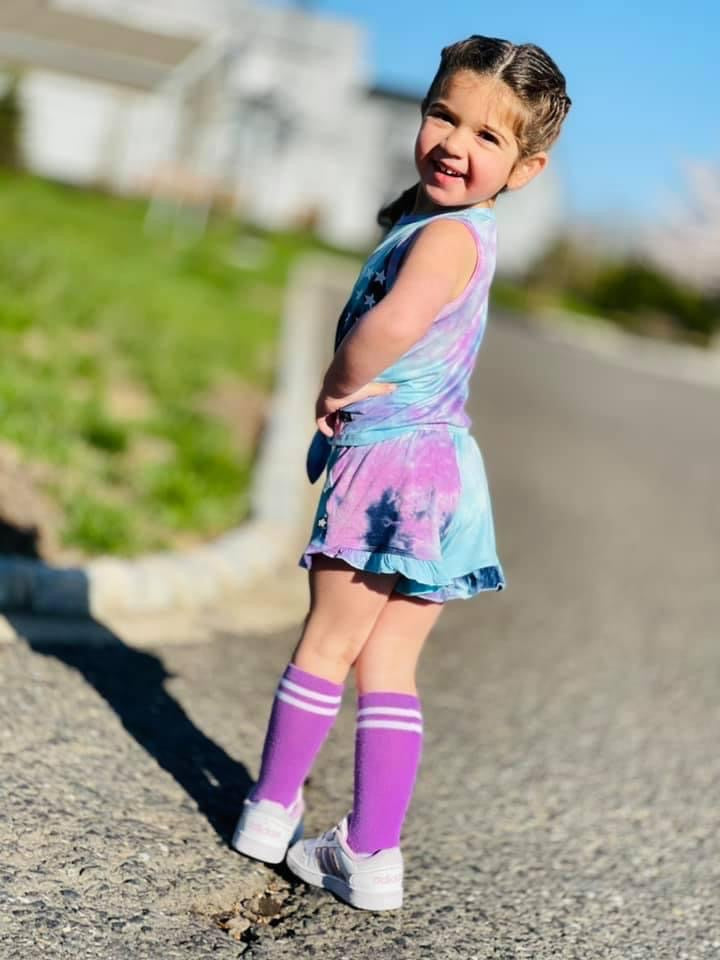 smiling girl wearing a tie dye outfit in the street