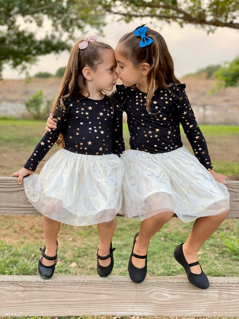 two young girls sitting on a fence wearing matching holiday outfits