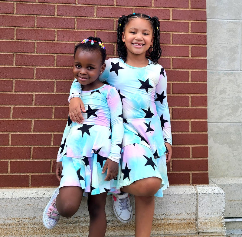 Two girls wearing matching blue and black starred tie dye dresses.