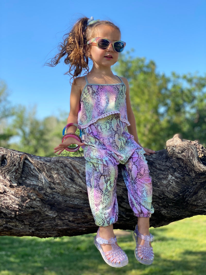 Young girl wearing sunglasses and a tie dye jumpsuit.