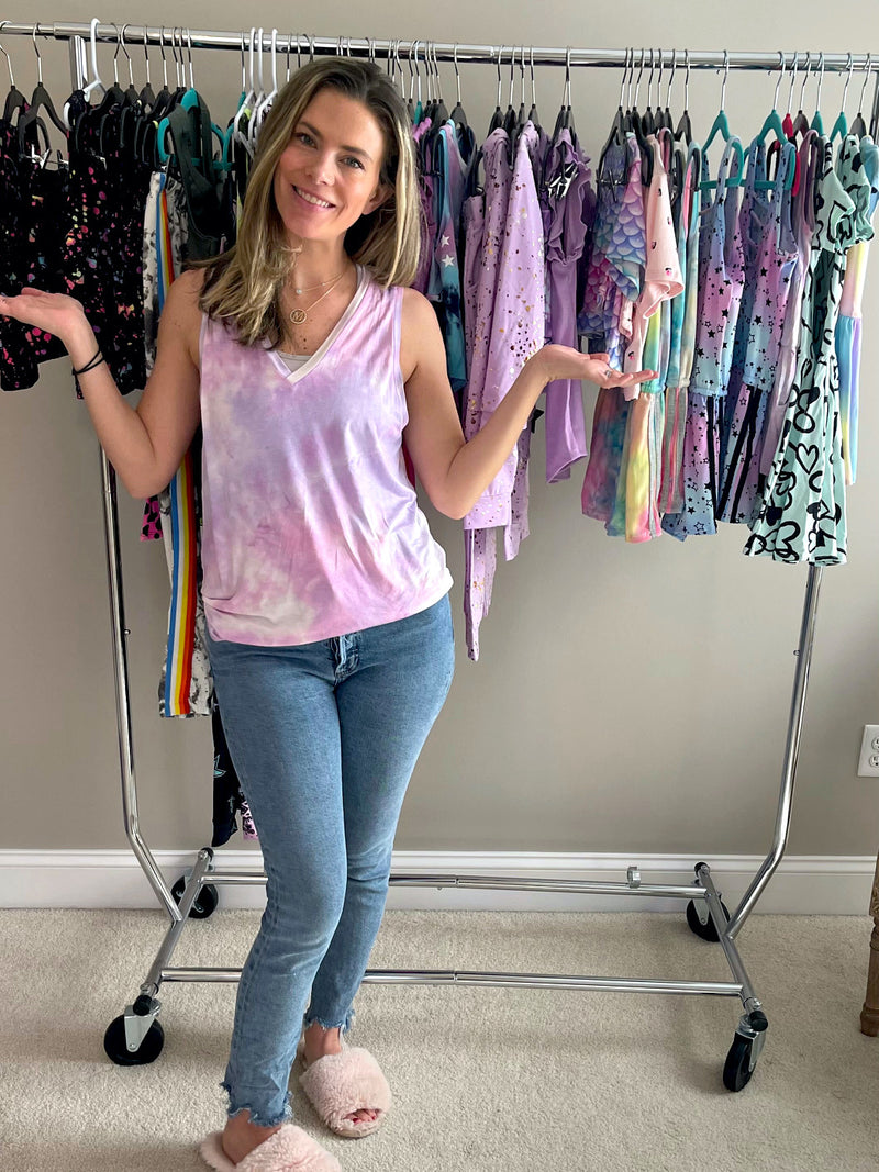 Mom holding her hands out next to a rack of children's clothing.