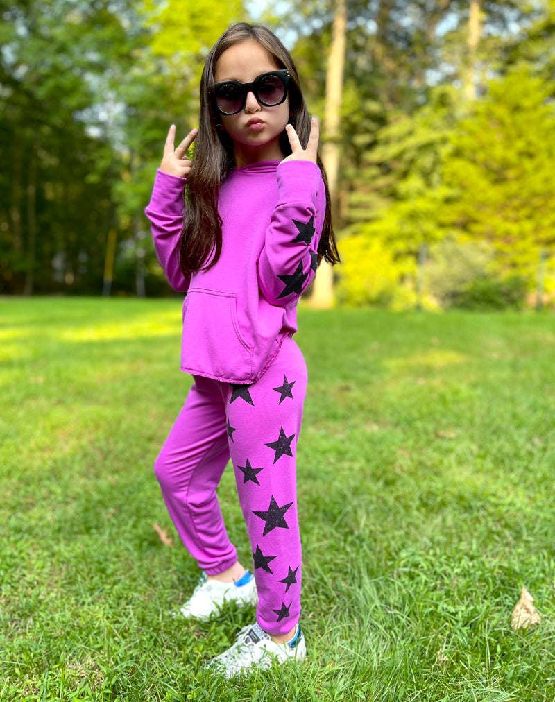 Young girl wearing a pink outfit with black stars on it.